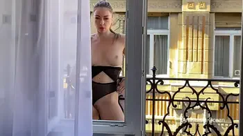 A woman undresses on a balcony in the city center. Public flashing.