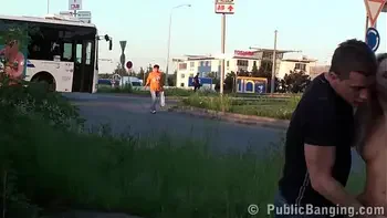 A cute blonde girl is fucked in public by 2 guys on the street with a blowjob sucking dicks and vaginal pussy sex penetration with all the cars and trucks passing by watching the risky orgy